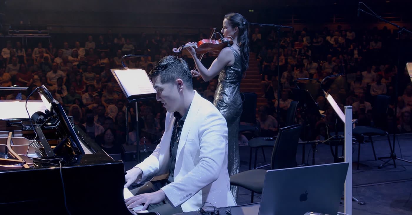 Lionel Yu performing with violinist Barbara in a grand concert hall